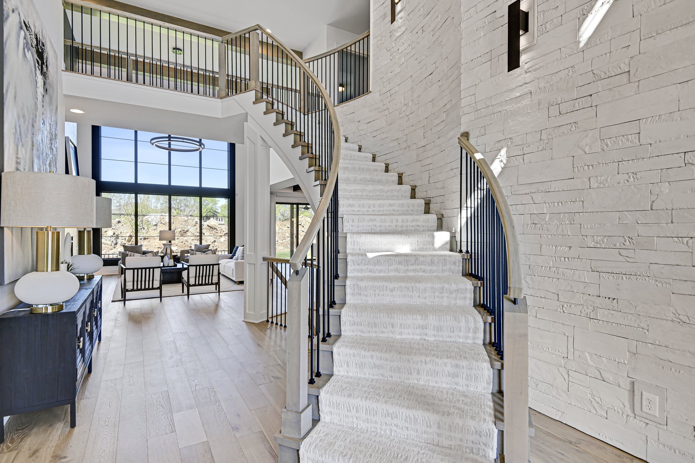 Curved staircase beside a white stone wall in a two-story JFE Construction home