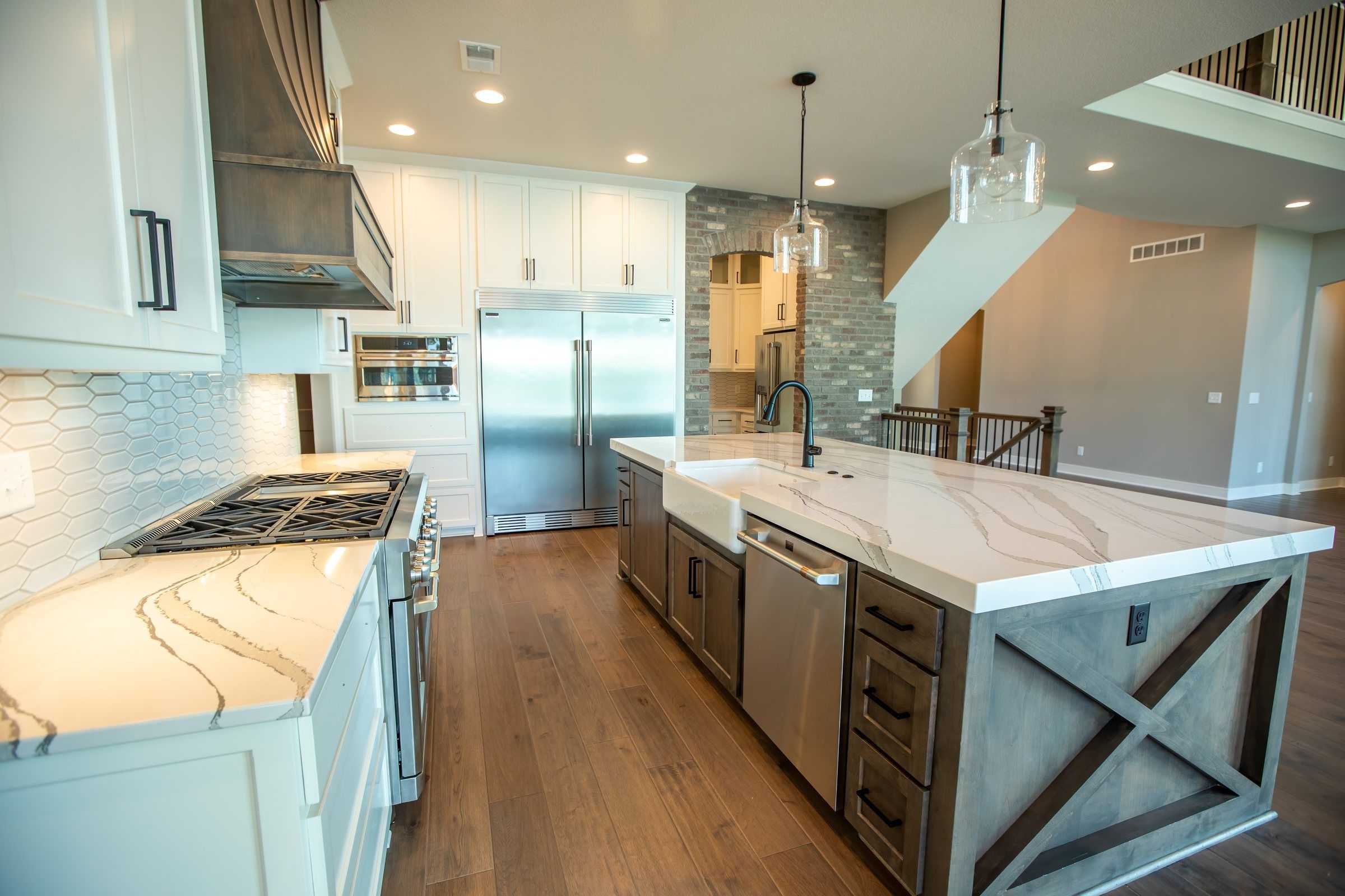Kitchen with a large marble island and farmhouse sink in a JFE Construction home